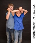 Small photo of Brothers having fun whilst posing. Boys portrait, young little cute and adorable kids, little obstreperous scamps. Poses, face expressions, ease, black background.