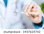 The doctor is holding medical mercury thermometer in the hospital. Hospital tool, equipment. Healthcare and medical concept.