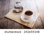 Cup of coffee on a wooden table with glass of water on the Sackcloth bags