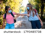 Small photo of Two Teenage Girls say hello touching hands elbow meeting in the Park on the way to School. New handshake due to Coronavirus pandemic safety protective behavior