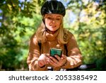 Using phone in forest for orientation. Female cyclist looking at gps map application in green Park. Selective focus on the smart phone in hands