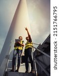 Small photo of Young man and woman maintenance engineer team working and holding the report in wind turbine farm. Generator station, renewable energy