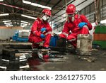 Male and female workers or scientists wearing red safety suits and gas masks undergoes cleaning and mopping up of spilled oil in the factory area for inspection in the laboratory.