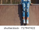 girl is sitting, wearing ripped jeans, hipster style, casual, clothes for youth, no face, lower part of body, sporty style. 