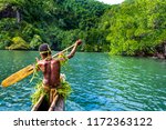 Yang sportive indigenous tribal boy with a paddle in a traditional canoe, natural green jungle with mangrove trees background, Melanesia, Papua New Guinea, Tufi