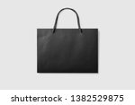 Mock up of a black paper shopping bag with handles on light grey background. High resolution.