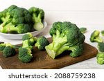 fresh green broccoli on wooden cutting board with knife. Broccoli cabbage leaves. light background. Flat lay.
