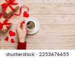 Flat lay of heart shaped cup of black coffee in the hands of women on colored background with copy space top view. Valentine day and holiday concept.