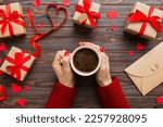 Flat lay of heart shaped cup of black coffee in the hands of women on colored background with copy space top view. Valentine day and holiday concept.