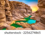 Small photo of Beautiful nature landscape with colorful sunset in canyon. Colorful nature scenery in mountain valley. Nature travel in extraordinary summer landscape. View of the stream flowing from the valley.