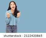 Small photo of Excited young asian female with raised hands celebrating success Portrait cheerful positive asian woman with raised hands and fists open mouth Girl get happy Pastel blue background, copy space