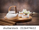 Tea concept with white tea set of cups and teapot with fresh tea on wooden background with copy space. 