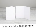 Two white greeting cards mockup, standing upright on a white wooden desk. Blank, open and closed cards template. 
