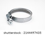 Small photo of Metal clamp close up. Clamp with cross screw. Steel element for repair and construction. Metal clamp on white background. Concept - sale of construction tools. Metal hose clip close up.