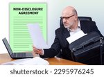 Small photo of Non-disclosure agreement. Man in office. Businessman signs contract. NDA document. Man is sitting at table with laptop. NDA business. Non disclosure agreement document. Signing NDA declaration.