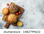 Tasty grilled home made burger with beef, tomato, cheese, bacon and lettuce on a light stone background with copy space. Top view. fast food and junk food concept. Flat lay