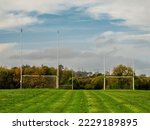 Small photo of Training pitch for Irish National sport camogie, hurling, rugby and Gaelic football with tall goal posts and freshly cut grass. Nobody. Cloudy sky. Popular activity.