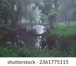 Small photo of Small concrete old bridge over a small river in a town forest park in a fog. Mistry surreal calm mood. Relaxing atmosphere and melancholic nature vibe.