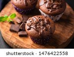 Double chocolate muffins covered with melted chocolate on a wooden background