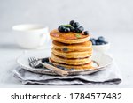Tasty pancakes with blueberries and honey on a plate. Grey background