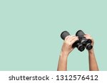 Hands holding binoculars on green background, looking through binoculars, journey, find and search concept.