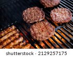Small photo of Smoky hamburger meat grilling for burgers. Fry on an open fire on the grill - bbq.Burgers and sausages Cooking Over Flames On The Grill.