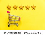 Simply flat lay design small supermarket grocery push cart for shopping with wheels and 5 gold stars rating isolated on yellow background. Retail consumer buying online assessment and review concept