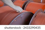 Small photo of Close-up of worker with wires on coils in factory. Creative. Worker numbers coils with wires at factory. Ready-made coils with rubber wires in industrial enterprise