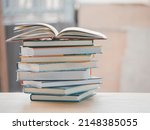 A simple composition of many books, stack or pile of books on wooden table, one of them open with copy space.