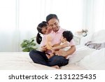 Small photo of The joy of an Asian single father taking care of two children, a daughter and a son. A 2-year-old is sitting on his father's lap and playing happily in bed. Concept Happy Family