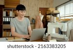 Small photo of Young Man Asian LGBTQ Tailor Shop Owner,The typist chats with the customer about cutting the dress, with a happy face,Small business Professional Design clothes to sell online.