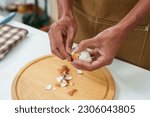Small photo of Close-up of a man's hand peeling a hard-boiled egg to prepare the salad and sandwiches for breakfast. Before going to work, gently peel off the shell of the egg until it's unappetizing.