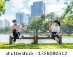Small photo of Asian young man and woman greet and say hello with they friend and wearing mask sitting distance of 6 feet distance protect from COVID-19 viruses for social distancing for infection risk in park.