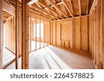 Small photo of Wood framing and flooring structure with golden sunlight shining through window frame at empty room. New construction house, framework of real estate development industry. Renovation, building concept