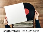 Playing vinyl records. Listening to music from vinyl record player. Retro and vintage music style. Woman holding analog LP record album. Stack of old records. Music collection. Music passion