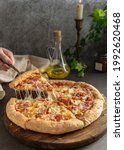 Small photo of selective focus. hot pizza with cheese and pepperoni. the girl pulls a slice of pizza with melted cheese stretching. vertical position, dark mood