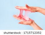 Small photo of Young girl hands with sticky purple slime on blue background, liquid wax for depilation, conceptual flyer banner with copy space, antistress relax, modern kids hobby oddly satisfying semi surreal asmr