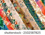 Small photo of Layers of beautiful silk fabric. Many different colorful fabrics are folded as a background. Delicate and lightweight silk fabric for sewing clothes.