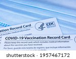 Small photo of Closeup. Covid-19 vaccination record cards issued by CDC, United States Centers for Disease Control and Prevention, on a blue disposable face mask - San Jose, California, USA - 2021
