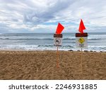 Scenic view of Haleiwa Beach with two warning signs, sharp coral, no swimming and red warning flags posted on a popular surf spot at  on Oahu Hawaii during winter storm.
