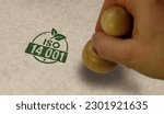Small photo of ISO 14001 certified stamp and stamping hand. Environment ecology standard certificate concept.