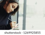 Small photo of Woman Make Notes And Look Around For Ideas. Portrait Of Stylish Smiling Woman In Winter Clothes Make Notes And Look Around For Ideas. Female Winter Style. - Image