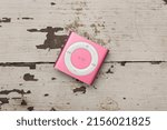 Small photo of Saint-Petersburg, Russia - May 10, 2022: Top view of small pink iPod Shuffle player on wooden table