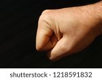 Small photo of a clenched fist isolated on dark background. Assault and battery concept image.
