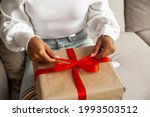 Christmas lifestyle and shopping and black friday concept. Close up hands of african american young woman opens box with christmas gift with red ribbon.