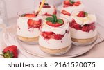 Small photo of Cheesecake with strawberries, cookies, oats, lactose and dairy free yogurt and mint in glasses on plate on table with golden spoon