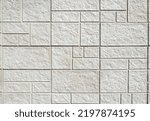Exterior stone wall cladding made by white rock panels in tile shape of differen sizes. Background and texture.