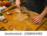 Female hand cut gingerbread dough with a sharp knife at kitchen. Traditional Christmas home bakery. Baking, cooking and christmas concept . High quality photo