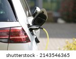 plug in adapter in car charge battery of electric car next to a charging station with yellow cable to refuel with renewable energy