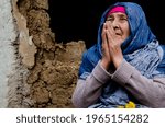 Small photo of Old grandmother in prayer portrait photo. Grandmother prays against the background of the ruins. Praying old woman in trouble. Old face of grandmother in prayer. Poverty and destitution